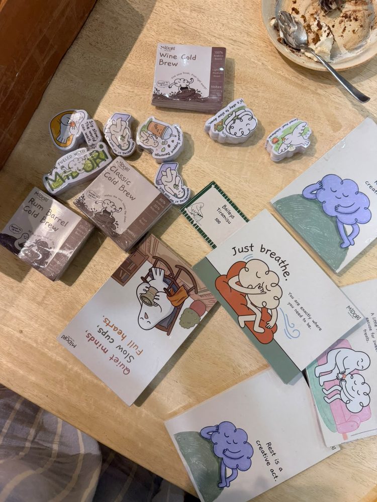 Midori cold brew packs on a table with die-cut character stickers and printed cards