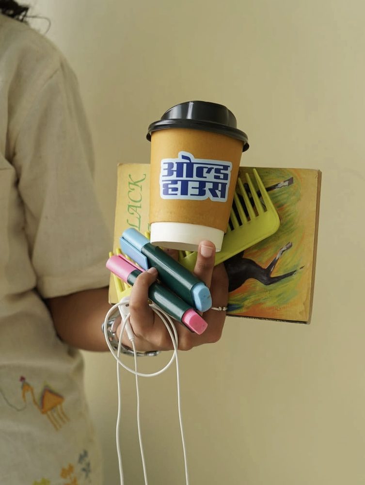 A branded Old House cup held against a book and markers